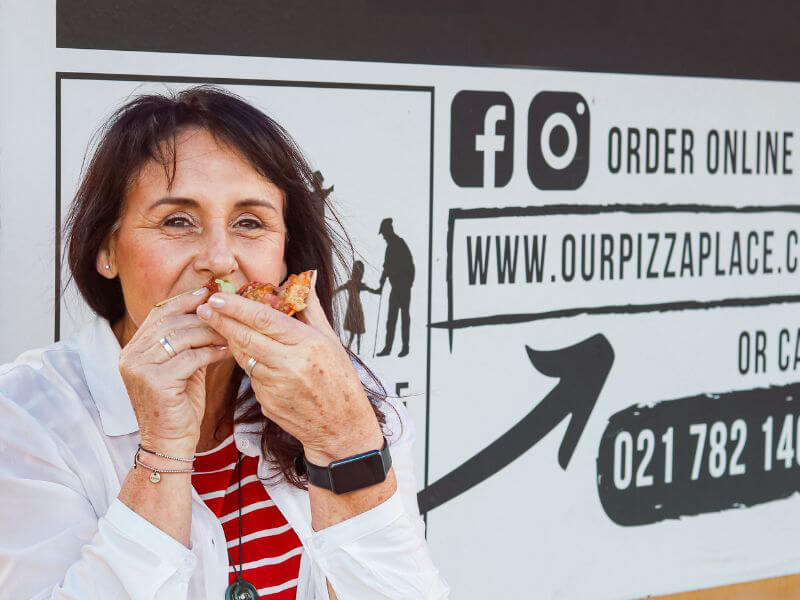 Woman enjoying a delicious slice of pizza in Fish Hoek